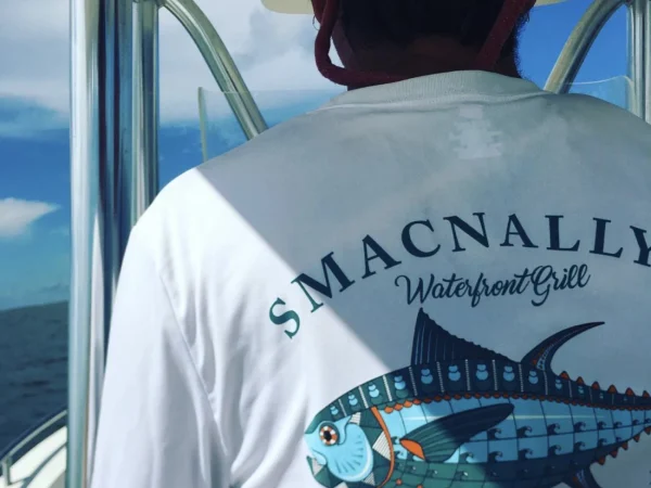 SmacNallys Waterfront Bar and Grill white longsleeve shirt being worn while driving a fishing boat